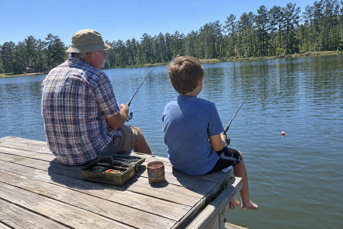 Grandfather and grandson fishing from the end of a small wooden dock on a sunny morning