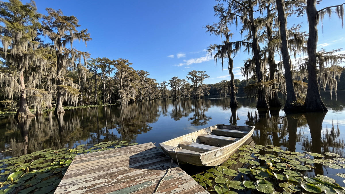 Still East Texas lake at early morning with a small aluminum boat tied to a wooden dock