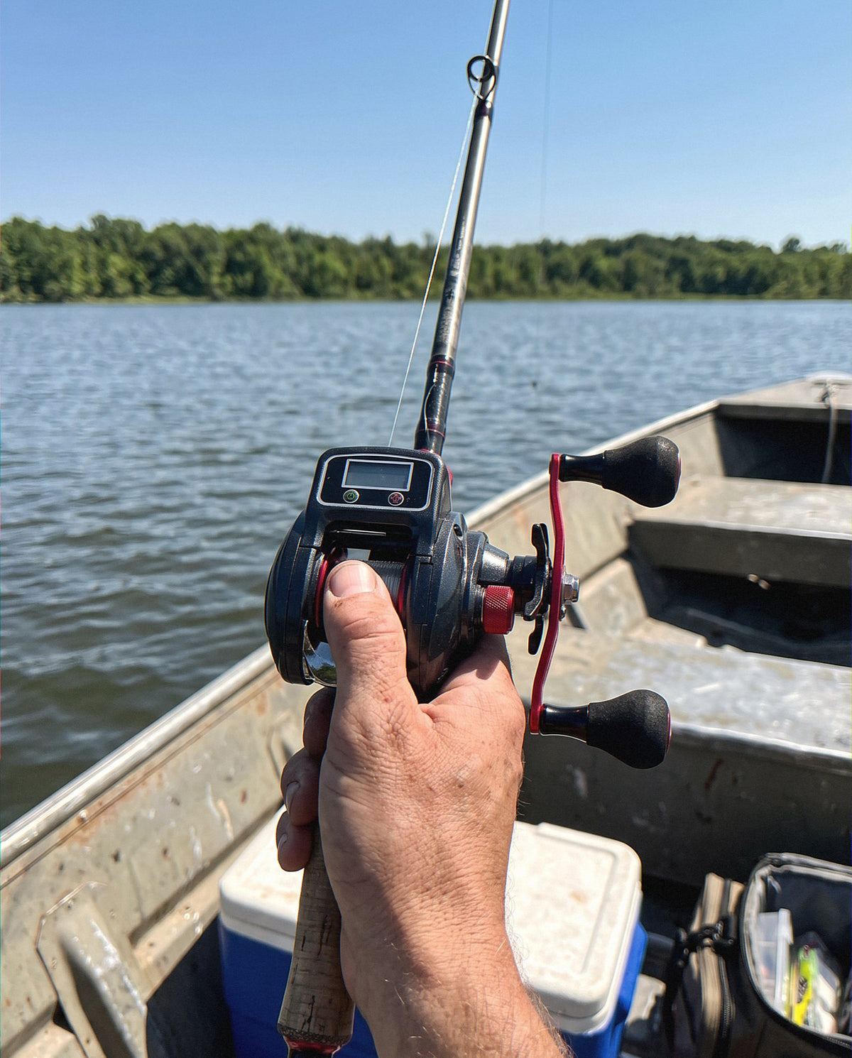 The Obalus Digital Reel Thrill on a casting rod in a jon boat