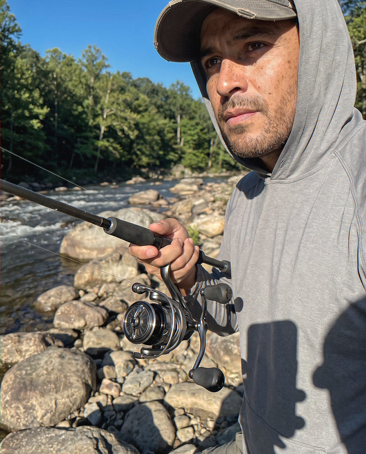 An angler on a river bank with the Obalus Fusion Grip spinning reel
