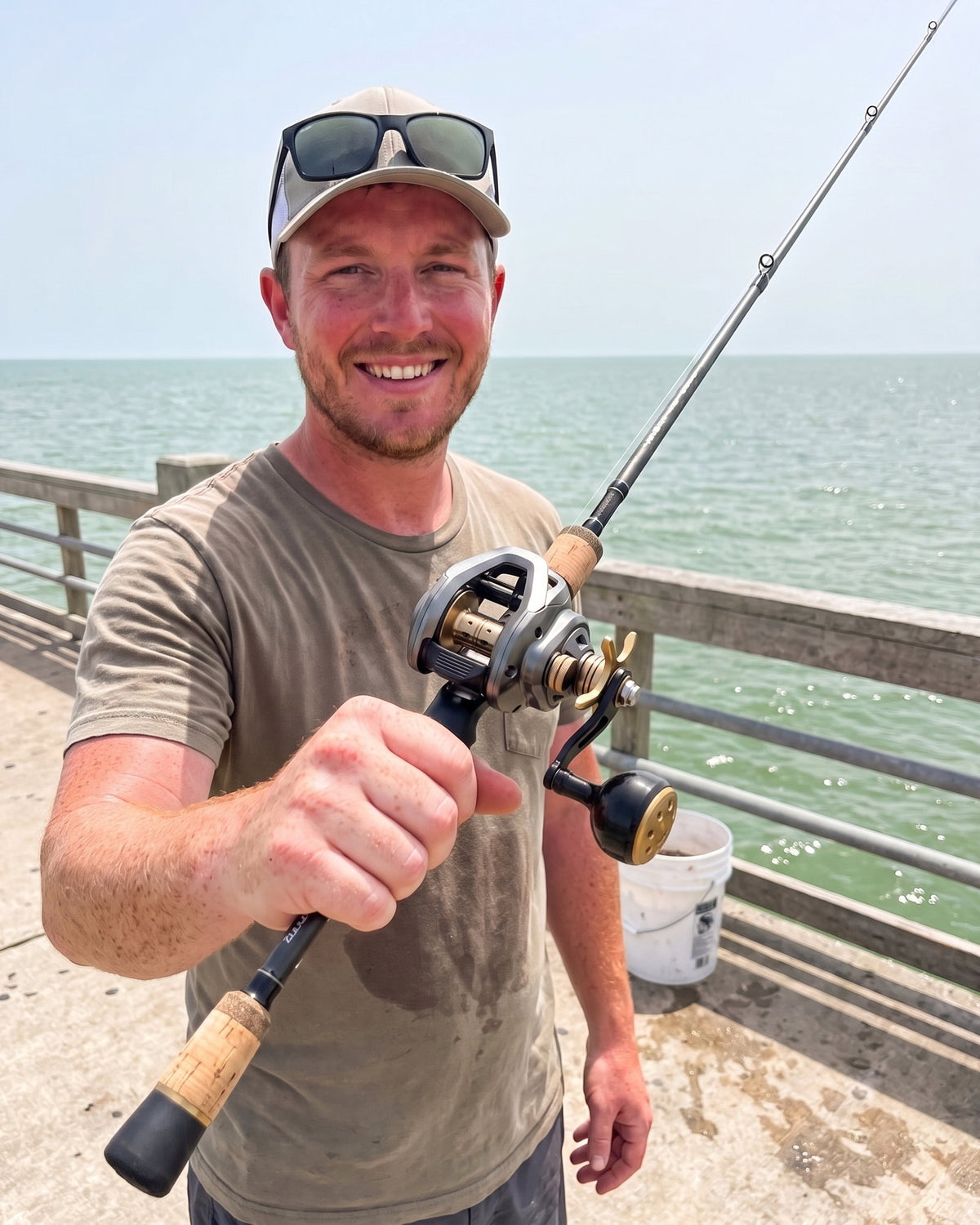 Obalus King Cast reel on a casting rod held up on a bass boat with the lake behind