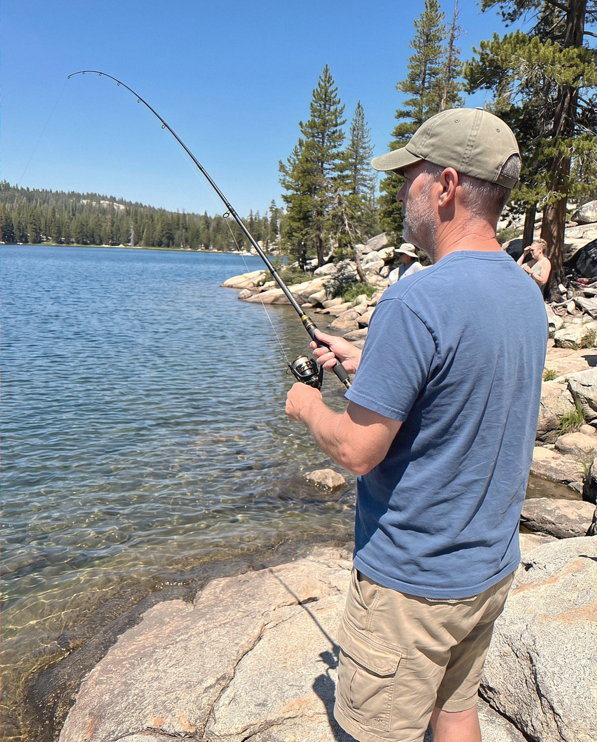 An angler fishing a clear lake with the Carbon Storm rod