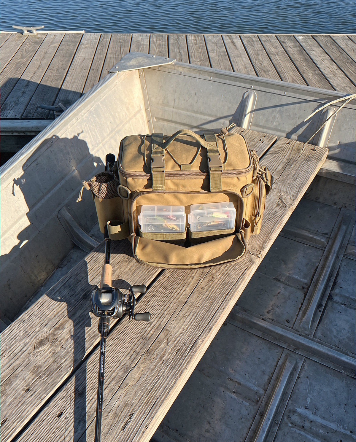 The Obalus Waterproof Tackle Bag on a jon boat bench with tackle boxes in the front pocket
